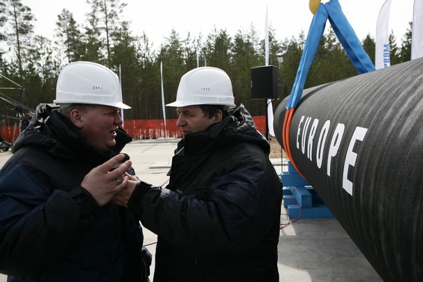 Workers stand by a pipe during a ceremony to mark the beginning of the construction of Nord Stream offshore pipeline