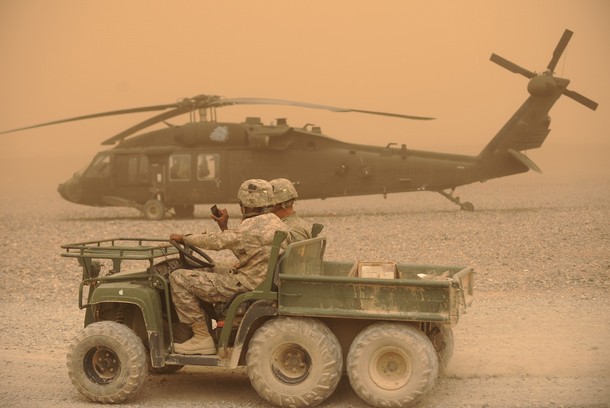 US Army soldiers drive past a Blackhawk helicopter in Kandahar, March 27, 2011.