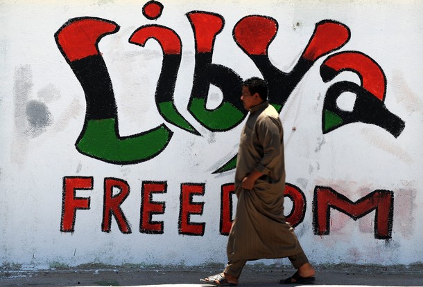 A Libyan man walks past graffiti in the eastern city of Ajdabiya, May 6, 2011.