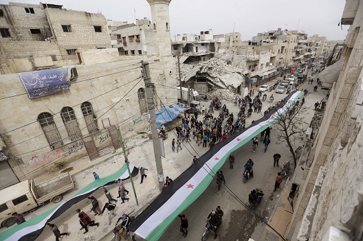 Protesters carry opposition flags as they march along a street during an anti-government protest in the rebel-controlled area of Maaret al-Numan town in Idlib province, Syria March 25, 2016. REUTERS/Khalil Ashawi
