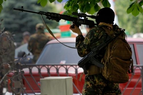 A fighter with the pro-Russian "Vostok Battalion" aims a sniper rifle at the Donetsk provincial government headquarters in Ukraine after the unit took control of it from other pro-Russian separatists on May 29. Chechen fighters from Russia told reporters in the city they arrived recently to join the Vostok unit. REUTERS/Yannis Behrakis