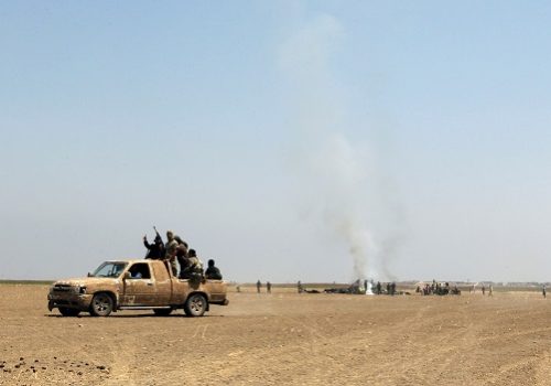 Fighters of the Syrian Islamist rebel group Jabhat Fateh al-Sham cheer on a pick up truck near the wreckage of a Russian helicopter that had been shot down in the north of Syria's rebel-held Idlib province, Syria August 1, 2016. REUTERS/Ammar Abdullah