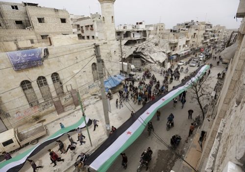 Protesters carry opposition flags as they march along a street during an anti-government protest in the rebel-controlled area of Maaret al-Numan town in Idlib province, Syria March 25, 2016. REUTERS/Khalil Ashawi