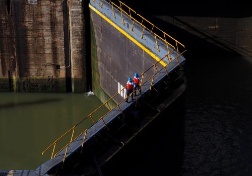 Two men walking across a floodgate.