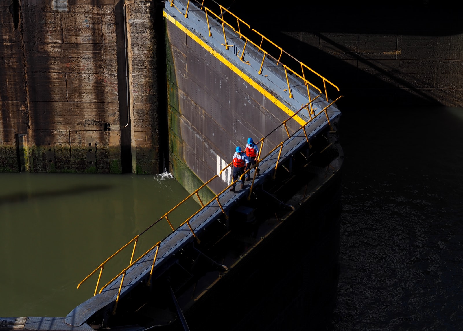 Two men walking across a floodgate.