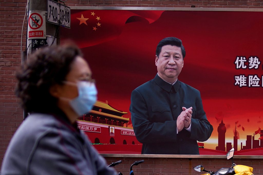 A woman wearing a protective mask is seen past a portrait of Chinese President Xi Jinping on a street as the country is hit by an outbreak of the coronavirus, in Shanghai, China March 12, 2020