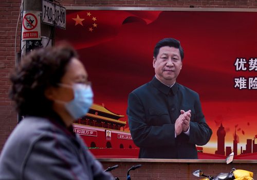 A woman wearing a protective mask is seen past a portrait of Chinese President Xi Jinping on a street as the country is hit by an outbreak of the coronavirus, in Shanghai, China March 12, 2020