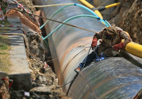 A worker helps put together a pipeline.