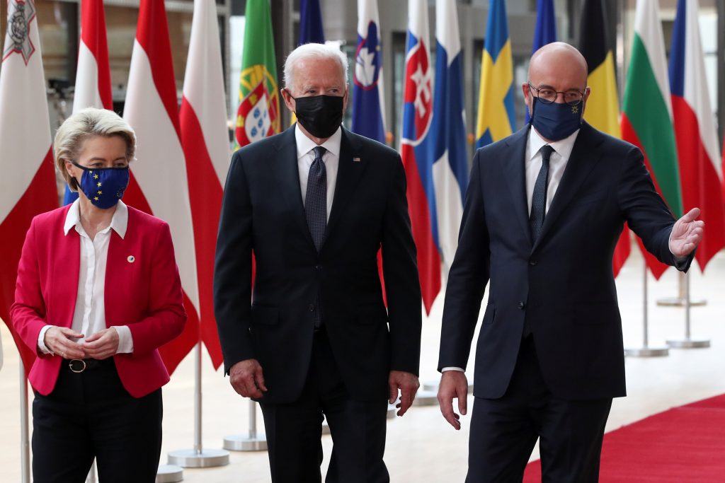 three people walking in front of flags