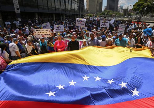 People hold a Venezuelan flag and placards as union workers, members of political opposition parties, and others participate in a protest against the government of Venezuela's President Nicolas Maduro during May Day, in Caracas, Venezuela May 1, 2023