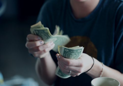 Person counting dollar banknotes