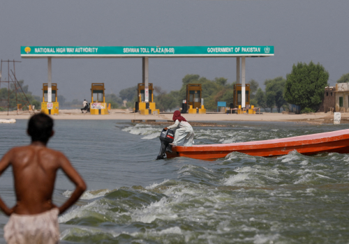 A man rides a boat past toll plaza amid flood water on main Indus highway, following rains and floods during the monsoon season in Sehwan, Pakistan.