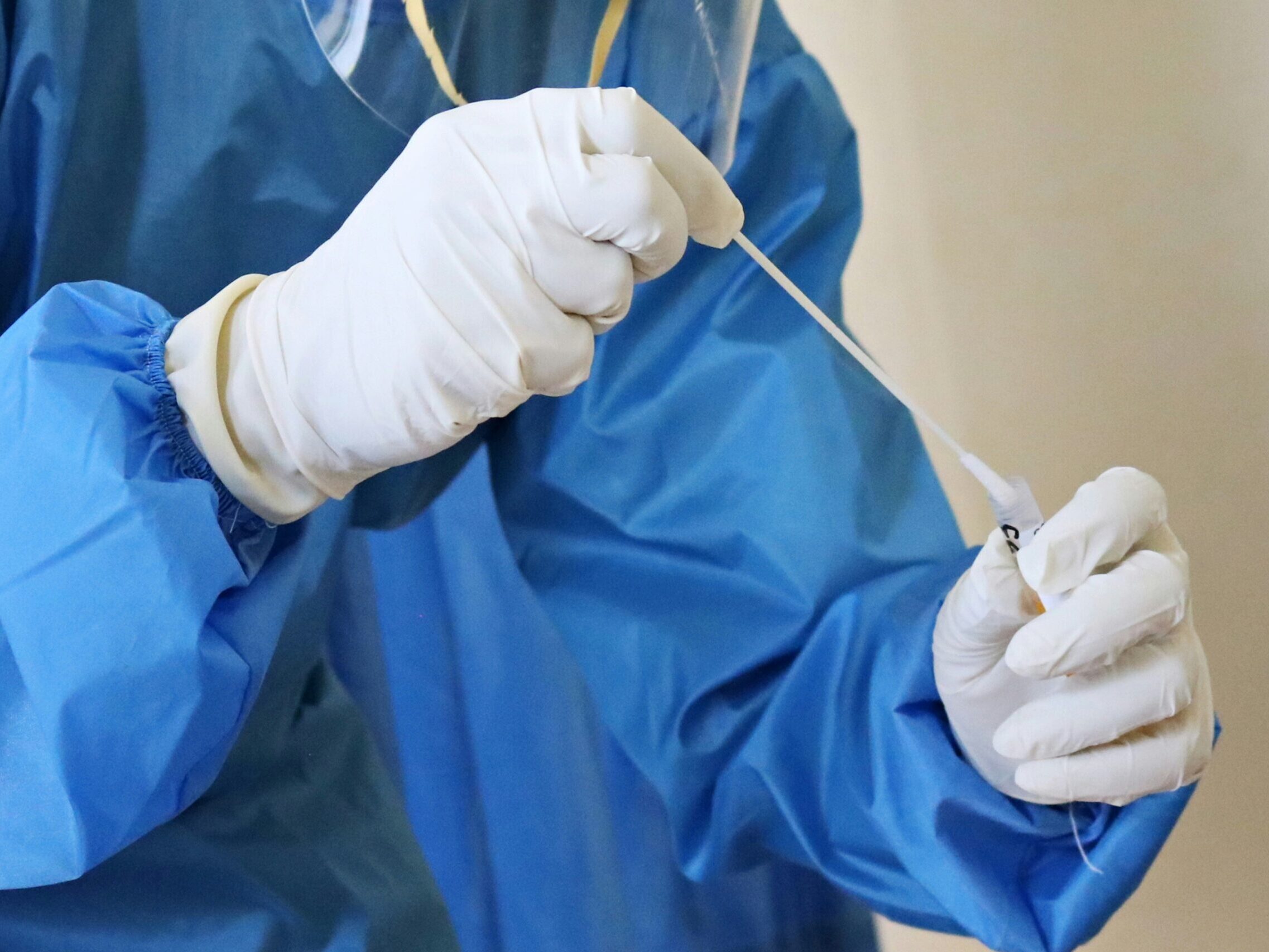 Medical personnel handling COVID swab test.