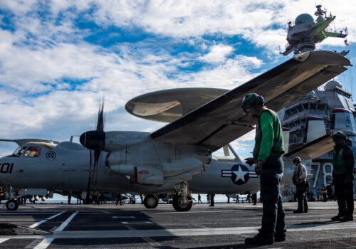 Man-standing-next-to-airplane-on-carrier