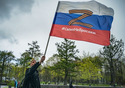 A man holds a Russian flag an orange and black "Z" symbol during the annual Immortal Regiment march in Moscow on Victory Day, May 9, 2022. The websites investigated in this report used the same version of the Z symbol in their online promotional materials. (Source: STR/NurPhoto via Reuters Connect)