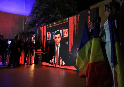 Supporters watch Leader of the radical right Alliance for the Union of Romanians (AUR) George Simion speak on a screen following the exit poll results during the Romanian presidential election, outside the Alliance for the Union of Romanians (AUR) headquarters in Bucharest, Romania